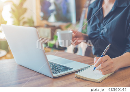 Woman is writing on a notebook with a pen 68560143