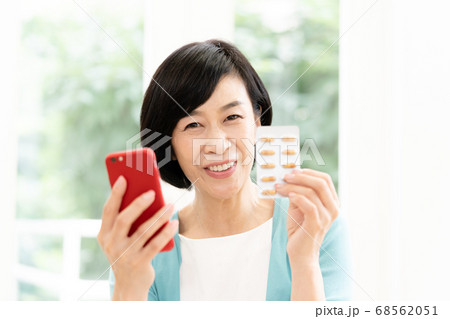 スマホとクスリを見るミドル女性 スマホとクスリを見るミドル女性 68562051