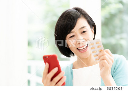 スマホとクスリを見るミドル女性 スマホとクスリを見るミドル女性 68562054