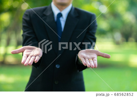 Handsome business man show blank hand in city park Handsome business man show blank hand in city park 68562852