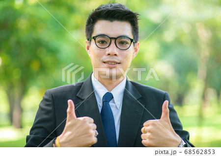 Handsome business man show blank hand in city park Handsome business man show blank hand in city park 68562853