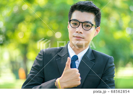 Handsome business man show blank hand in city park Handsome business man show blank hand in city park 68562854