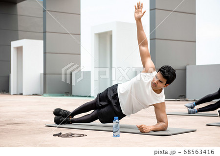 Athletic Indian man doing side plank exercise outdoors 68563416