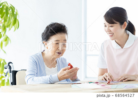 介護イメージ　折り紙を折るシニア女性と介護士 68564527