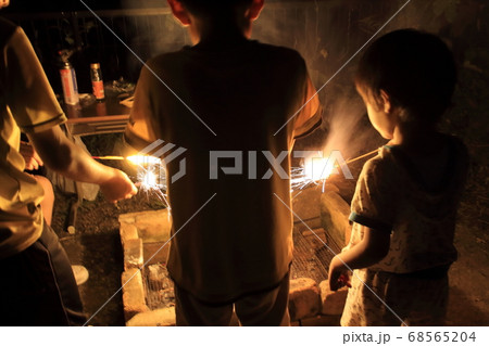 夏の夜に手持ち花火を楽しむ子供たちの写真素材