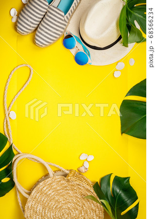 Straw hat, camera, bag, summer shoes, sunglasses, shells and tropical leaves over yellow background Straw hat, camera, bag, summer shoes, sunglasses, shells and tropical leaves over yellow background 68566234