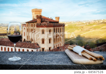 Chalice of wine with breadsticks and the castle of Barolo, Italy 68567526
