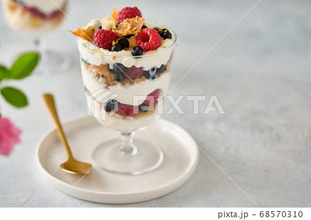 Dessert in a glass with raspberries and blueberries and cream. Dessert in a glass with raspberries and blueberries and cream. 68570310