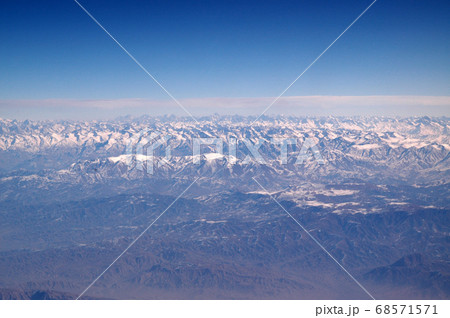 Mountains with snowy peaks on blue sky, aerial 68571571