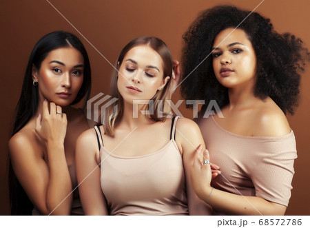 young pretty asian, caucasian, afro woman posing cheerful together on brown background, lifestyle diverse nationality people concept young pretty asian, caucasian, afro woman posing cheerful together on brown background, lifestyle diverse nationality people concept 68572786