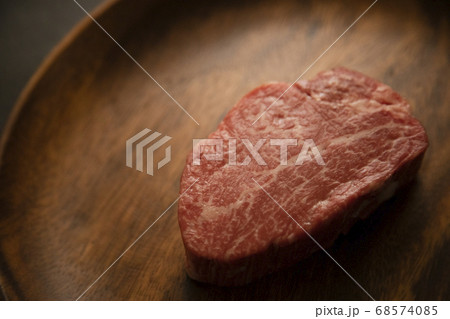 アカシアプレートに乗せた生の肉厚牛フィレステーキ 68574085