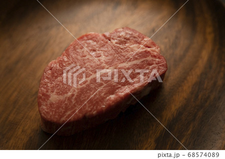 アカシアプレートに乗せた生の肉厚牛フィレステーキ 68574089