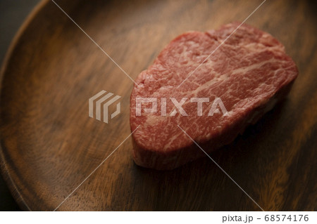 アカシアプレートに乗せた生の肉厚牛フィレステーキ 68574176