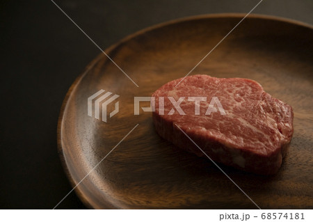 アカシアプレートに乗せた生の肉厚牛フィレステーキ 68574181