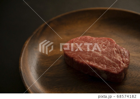 アカシアプレートに乗せた生の肉厚牛フィレステーキ 68574182