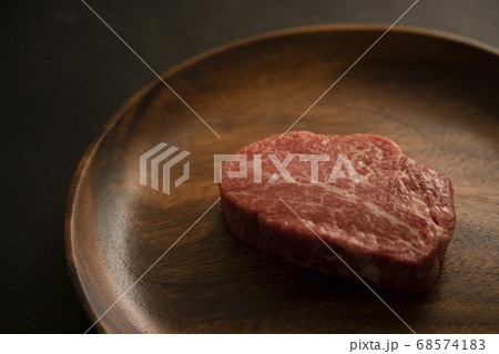 アカシアプレートに乗せた生の肉厚牛フィレステーキ 68574183