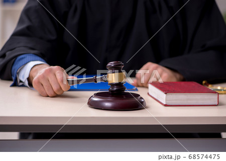 Young male judge working in courthouse 68574475
