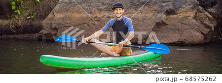 Joyful man is training SUP board in river on a sunny morning. Stand up paddle boarding - awesome active outdoor recreation BANNER, LONG FORMAT Joyful man is training SUP board in river on a sunny morning. Stand up paddle boarding - awesome active outdoor recreation BANNER, LONG FORMAT 68575262