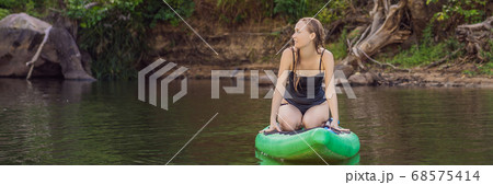 Side view picture of a woman sitting and relaxing on the sup board. Surfer woman resting BANNER, LONG FORMAT Side view picture of a woman sitting and relaxing on the sup board. Surfer woman resting BANNER, LONG FORMAT 68575414