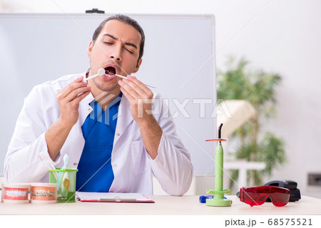 Young male dentist working in the clinic Young male dentist working in the clinic 68575521