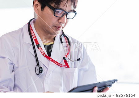 タブレットでオンライン診察を行う医師 68576154