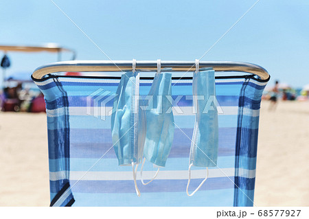 masks hanging from a deck chair on the beach 68577927