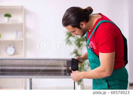 Young male contractor repairing heater indoors 68578023