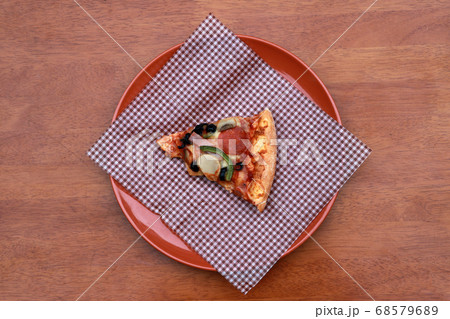 A piece of triangle Pizza place on brown scotch paper  in the brown round plate 68579689