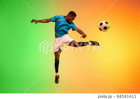 Male soccer, football player training in action isolated on gradient studio background in neon light Male soccer, football player training in action isolated on gradient studio background in neon light 68581411