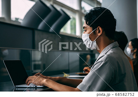 オフィスのカウンターでソーシャルディスタンスをとって仕事するマスクをしたビジネスパーソン 68582752