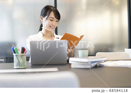 オフィスの席でスケジュール帳を確認する女性 68584118