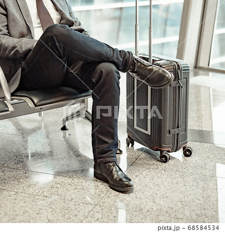 man waiting for his flight at the airport and looking at a mobile phone man waiting for his flight at the airport and looking at a mobile phone 68584534