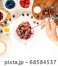 Top view showing hands eating porridge with honey nuts, blueberries on white wooden table selective focus, blurred background Good morning - healthy breakfast background 68584537