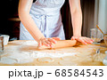 Female hands rolling out dough on kitchen table, close up 68584543