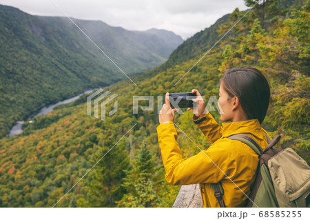 Hike woman hiker taking picture with phone of river view from top of trail hiking in Parc National de la Jacques Cartier, Quebec, Canada autumn travel camping lifestyle 68585255
