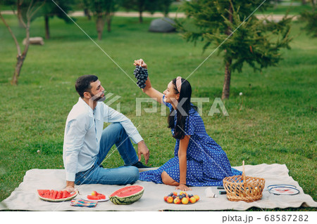 Young adult woman and man couple picnic with grape at green grass meadow in park Young adult woman and man couple picnic with grape at green grass meadow in park 68587282
