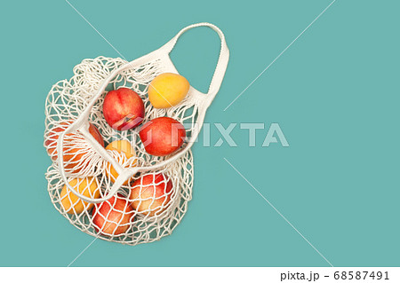 Peaches and apricots in eco bag on a blue background 68587491