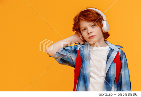 Modern schoolboy listening to music in headphones. Modern schoolboy listening to music in headphones. 68588886