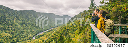 Travel couple hikers tourists taking photo with camera at view of mountain landscape in Autumn forest Parc de la Jacques Cartier, Quebec, Canada. Panorama banner background Travel couple hikers tourists taking photo with camera at view of mountain landscape in Autumn forest Parc de la Jacques Cartier, Quebec, Canada. Panorama banner background 68592957