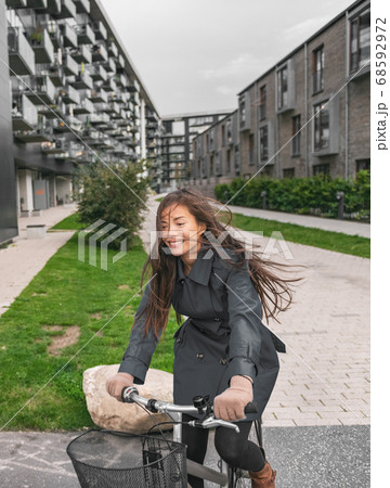 City bike Asian girl happy riding bicycle commuting outside condo apartment building street 68592972