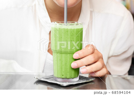 Matcha green tea smoothie cold dessert shake drink woman drinking with straw at cafe table 68594104