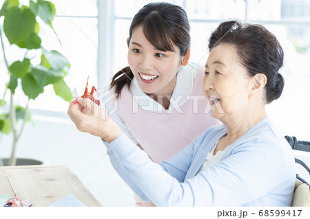 介護イメージ　折り紙を折るシニア女性と介護士 68599417