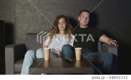 Beautiful girl and a young man sitting on the couch and watch TV. People relax on the couch. Beautiful girl and a young man sitting on the couch and watch TV. People relax on the couch. 68601532
