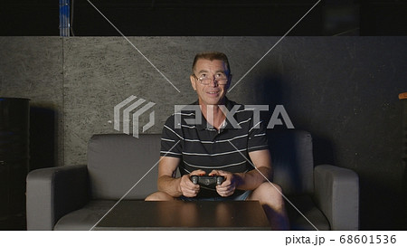 Joyful adult man playing video game alone entertaining at home enjoying gaming Joyful adult man playing video game alone entertaining at home enjoying gaming 68601536
