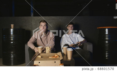 Two gamers in front of the screen are playing together in the online battle Two gamers in front of the screen are playing together in the online battle 68601570