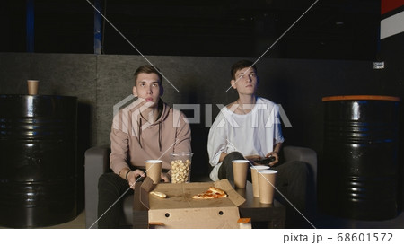 Two gamers in front of the screen are playing together in the online battle Two gamers in front of the screen are playing together in the online battle 68601572