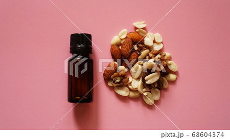 Bottle of oil and nuts on pink background 68604374
