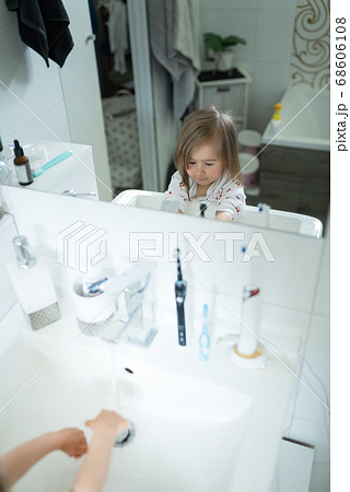 Cute little girl 2-3 years old washing hands with soap and water in bright bathroom. Mirror reflection Cute little girl 2-3 years old washing hands with soap and water in bright bathroom. Mirror reflection 68606108