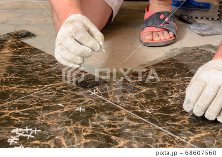 A man sets crosses between installed tiles 68607560