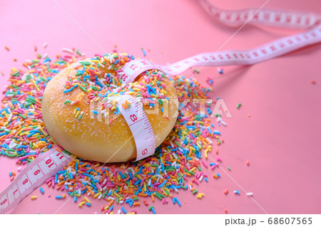 Close up of donuts and measurement tape on pink background. Close up of donuts and measurement tape on pink background. 68607565